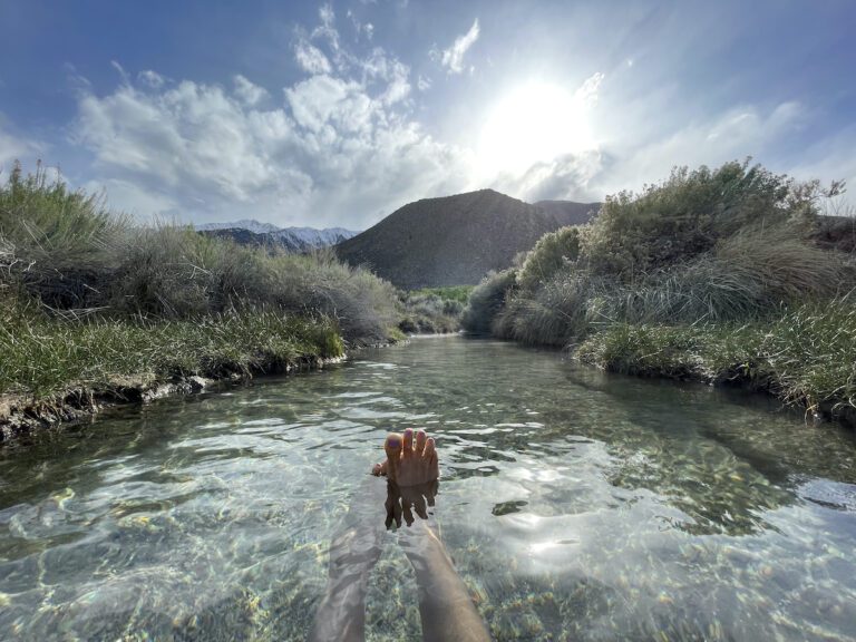 A woman soaks in a natural hot spring with her feet up