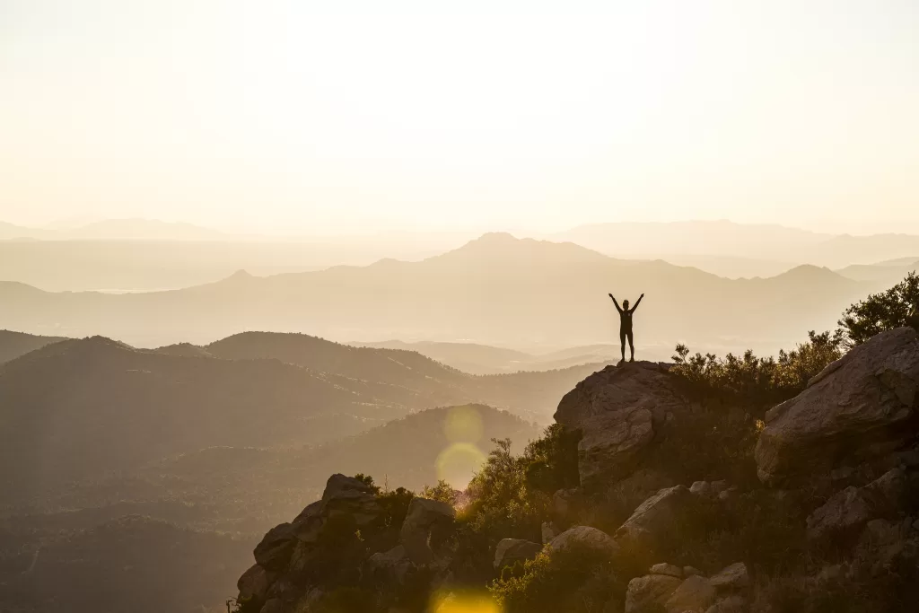 woman on the edge of cliff with arms raised. why do we need nature. solitude. hsp. introvert. 