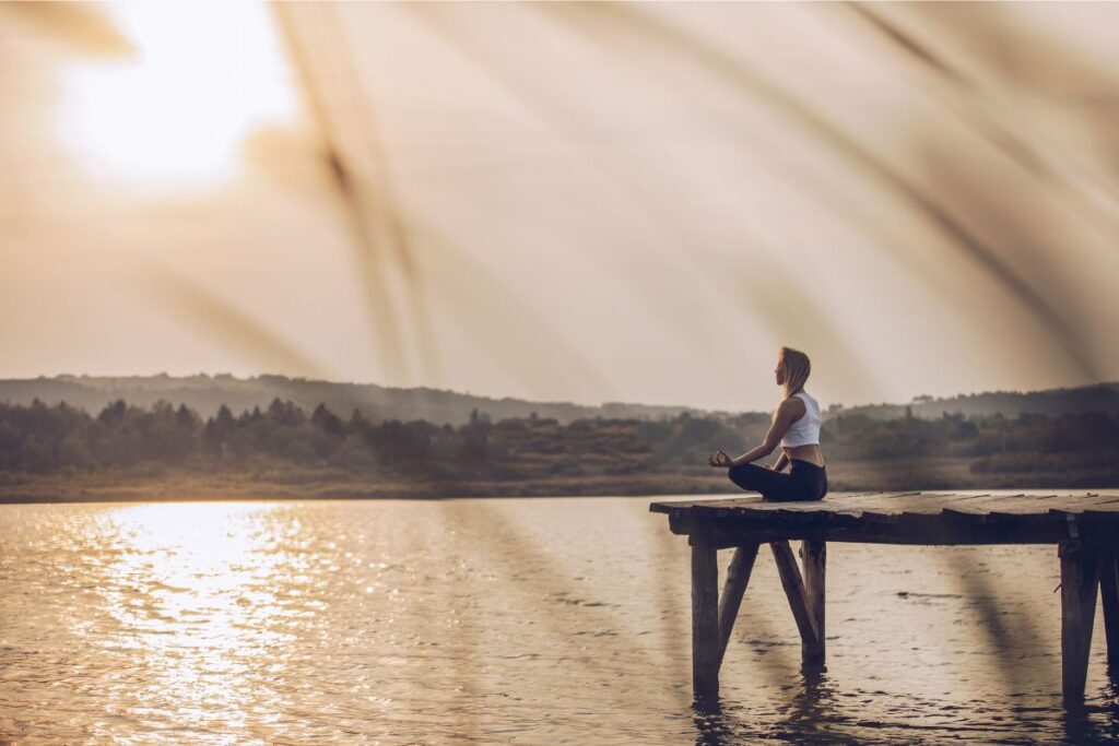 woman meditating on a dock