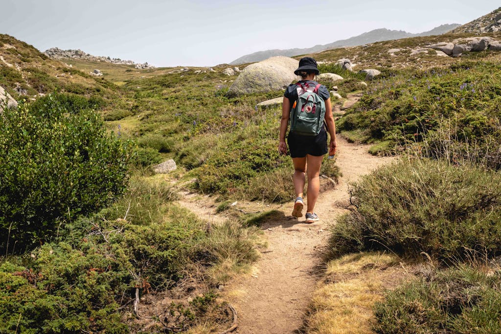 A person hiking through the scenic trails of Corsica's countryside, surrounded by lush greenery.